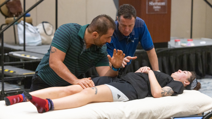 An image of a massage therapy educator demonstrating a technique for a student.