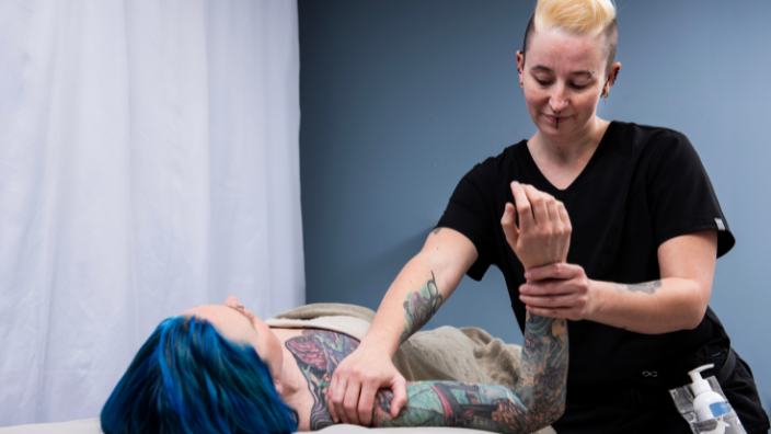 An image of a massage therapist stretching a client's shoulder.