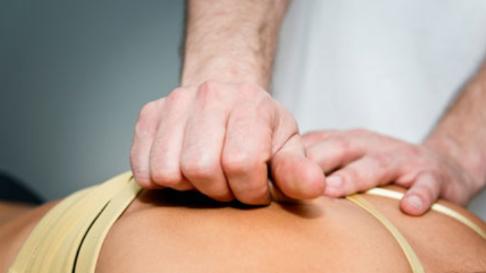 closeup of massage therapist administering fascial massage on upper back