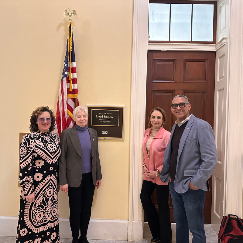 an image of four people standing and smiling in a government building.