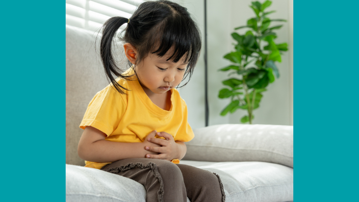 An image of a young girl holding her stomach and looking sad.