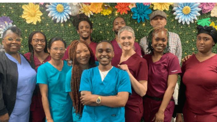 group of men and women massage therapist students posing by a flower wall