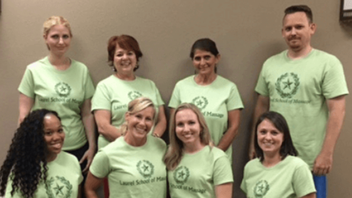 group of students wearing green shirts that say Laurel School of Massage posing for camera