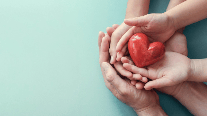 three sets of hands cradling a heart