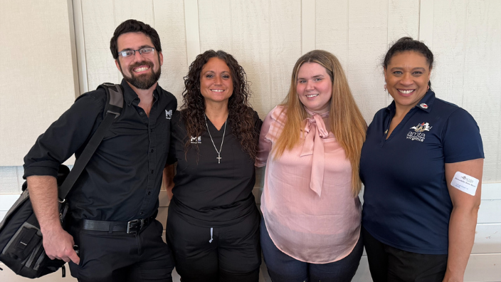 An image of four people, one man and three women, at the Virginia AMTA Chapter Conference.