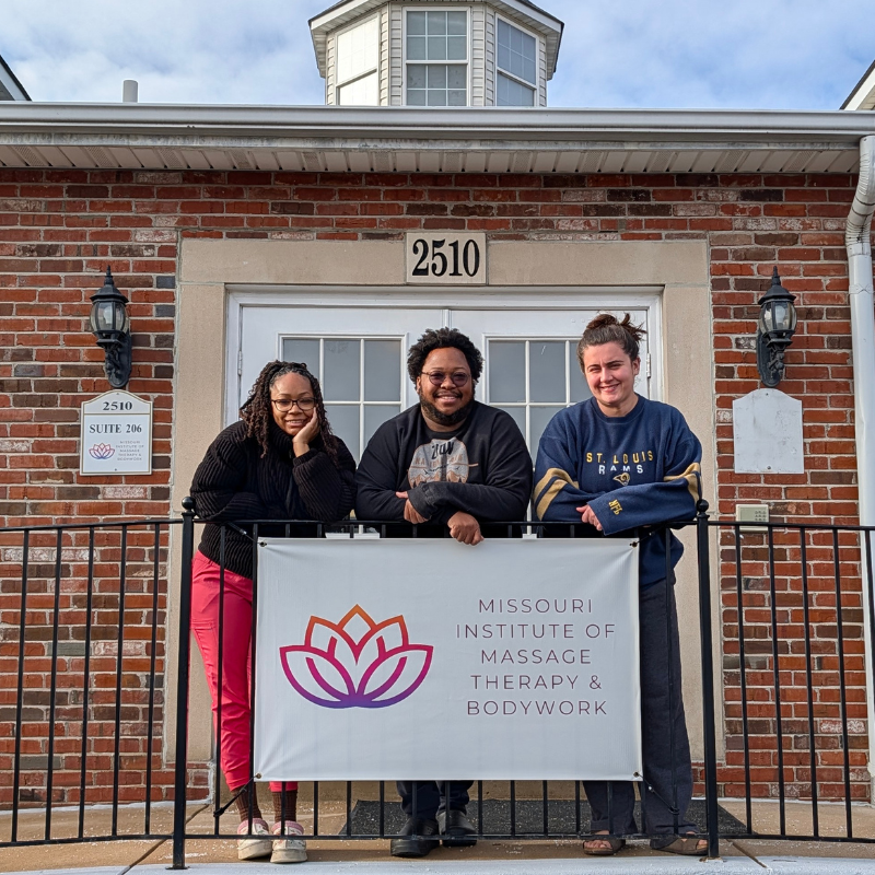group of three men and women posing outside a building holding a sign that says Missouri Institute of Massage Therapy and Bodywork