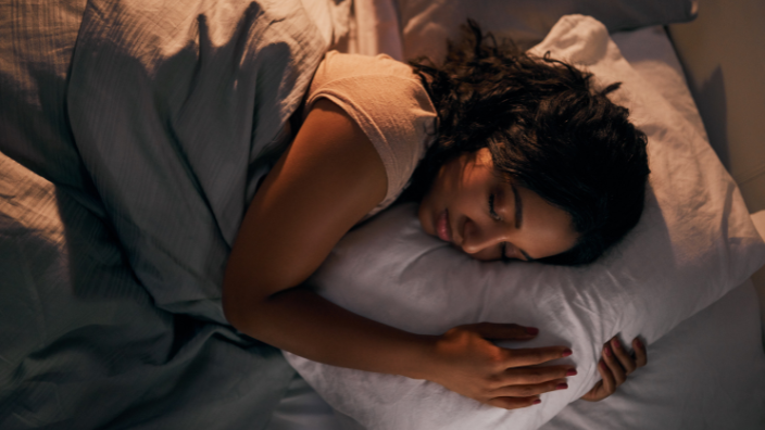 An image of a woman sleeping happily on her side.
