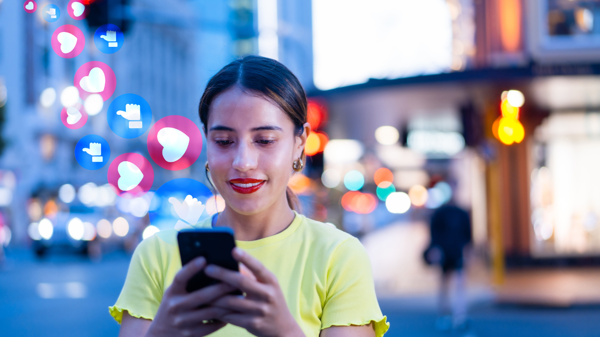 An image of a woman looking at her phone, social media reactions emerge from the phone.