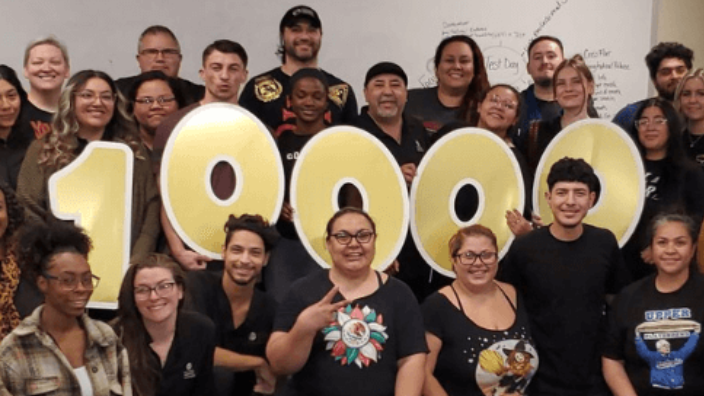 group of students posing while holding the number 10,000 in a cardboard cut outs