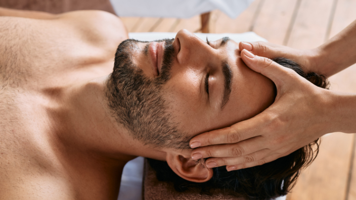 An image of a man smiling as he receives a scalp massage.